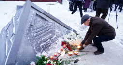 Cilvēki noliek sveces pie pieminekļa "1991. gada barikāžu piemiņas zīme" 1991. gada barikāžu atceres pasākuma laikā pie Saeimas nama.