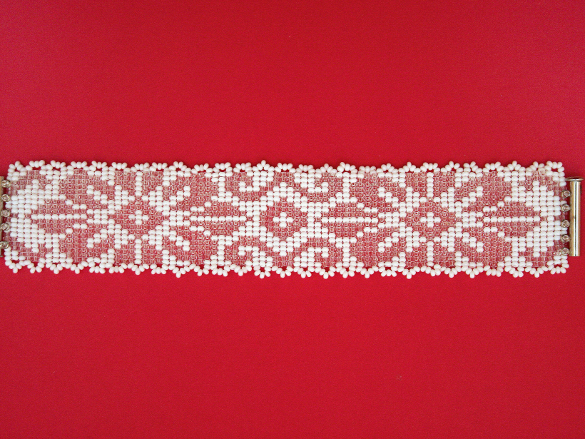 Baltajai rokassprādzei īpašu šarmu piešķir caurspīdīgās pērlītes.