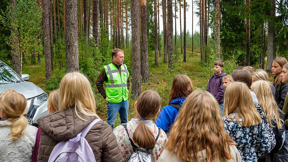 Daugmales skolēni ar interesi klausās LVM darbinieku stāstos par norisēm mežā.