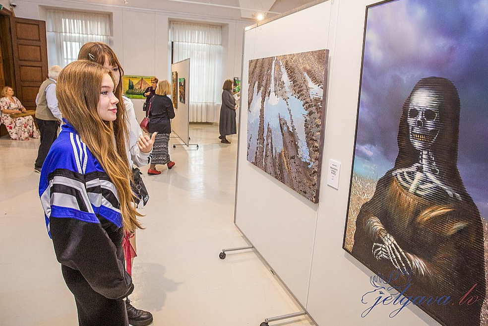 Izstādes zālē pirmais darbs no labās: Varis Dzērve, Arta Ozola-Jaunarāja, "Mīnēto rudzu lauku Džokonda”, 2023, a. e., akrils, 120x80 cm. Otrs darbs: Ingrīda Ivāne, "Pavasaris. Dubļu eņģeļi", 2023, a. akrils, 90x120 cm ( Žūrijas komisijas priekšsēdētāja simpātiju balva).