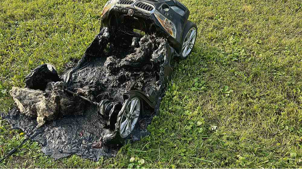 Sadegušais bērnu elektromobilis ar litija jonu akumulatoru – ugunsgrēka izcelšanās vieta. Foto uzņemts pēc ugunsgrēka, laukā pie ēkas.