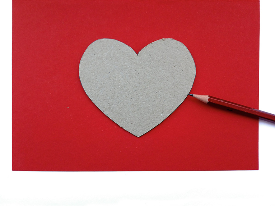 1. Uz pusēm salocītam sarkanajam kartonam priekšpusē uzliek šablonu sirds formā un apvelk tā kontūru.